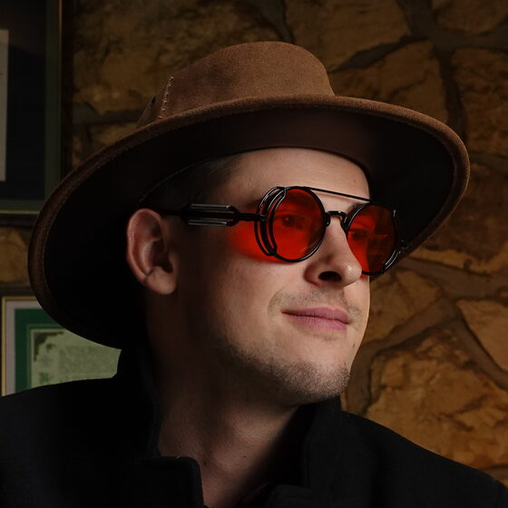 Jamie Williamson, in a felt hat and red-lensed glasses.